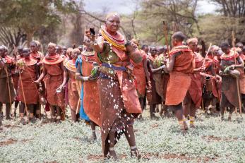 A woman spilling milk onto the parched landscape as an offering.