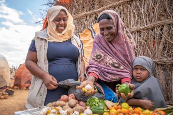 Mercy corps ceo tjada d’oyen mckenna and a villager sorting vegetables.