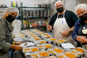 People preparing meals in a commercial kitchen.