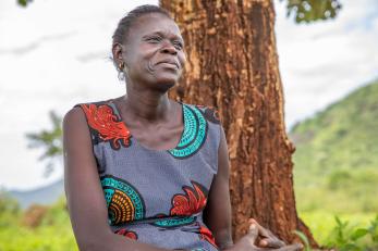 A person sits in the shade of a fruit tree on their property in uganda.