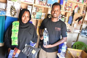 A person displays some of the items from their shop that can be purchased with a basic needs wallet in in kampala, uganda.