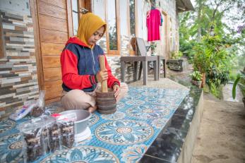 A person preparing cascara, a tea made from coffee shells, in front of their home. 