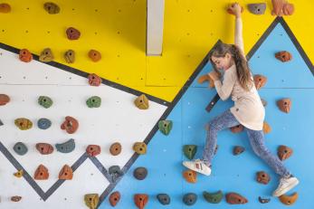 A young person traversing a climbing wall.