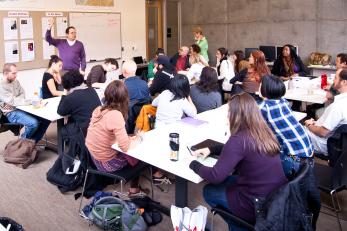 A man presenting to a room full of adults