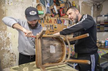 September 2023, dnipro, ukraine. a person works with their team to repair a chair in their furniture workshop.