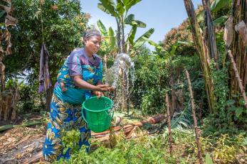 A farmer and mother waters her garden.