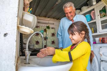 A parent watching their child wash their hands.