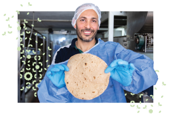 Man displays lebanese bread he has baked.