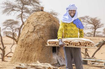 A person holiding a tray of baked goods.