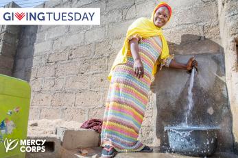 A person using a spigot to fill a vessel with water.