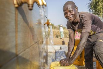 A person gets water from a water point constructed by mercy corps., where he regularly has conversations with herders and fosters relationships.