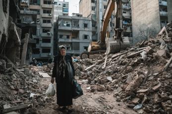 Lebanese woman walks through the rubble of a city street.