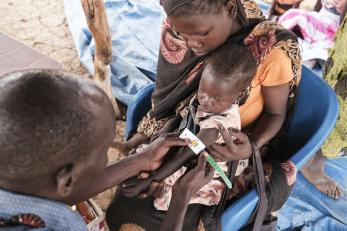 A child’s arm is measured for malnutrition at a clinic in thobo camp.
