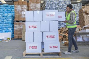 A mercy corps team member loads a pallet with food kits to be delivered in gaza.