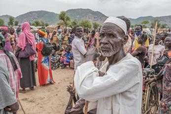 A crowd of people wait to receive food cards after registering as new arrivals at the agiri internal displacement camp.