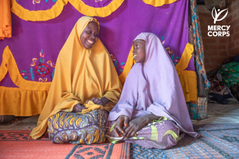 A mother and daughter face each other smiling.