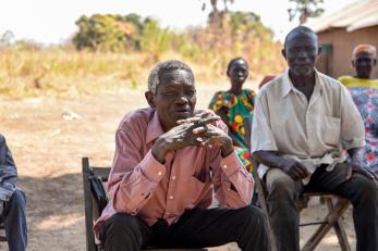 A man is seated at a community meeting in south sudan