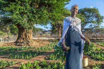 A woman stands near her garden in kenya