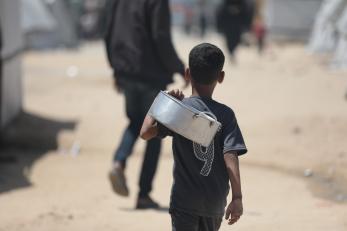 A child carries an empty pot along the streets of palestine