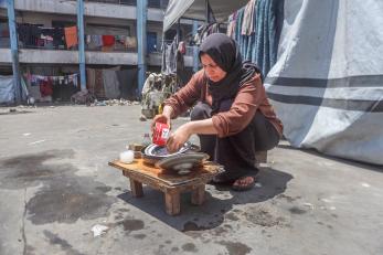 A woman in gaza cleans her family's food bowls