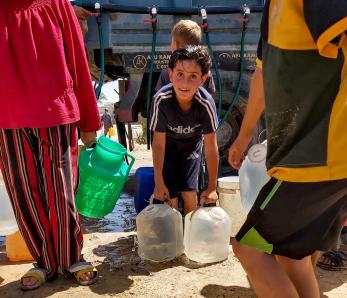 A palestinian boy prepares to carry water containers