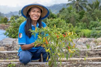 A woman in indonesia poses in a garden with one of her plants
