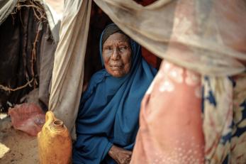 An elderly woman in a makeshift home poses in somalia