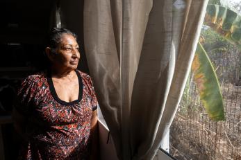 A woman looks out the window of her home in colombia