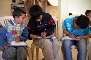 Boys sitting next to each other, drawing in books