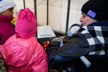 Khalid shares the space heater in one of mercy corps' shelters with two young girls so they can all warm up from the cold.