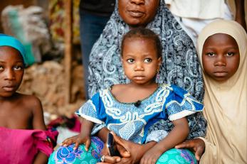 A woman is pictured with a young girl on her lap and two other girls to each side