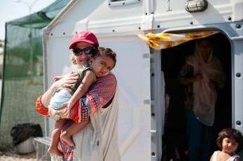 Mercy corps employee holding a young child