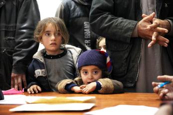 Two small children looking over a desk