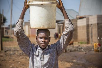 Jummai's son, abdullahi, carrying a bucket for water