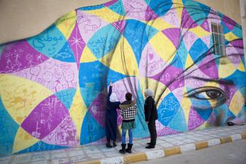 Heba and raghad show a mercy corps team member where they painted on the school's mural.