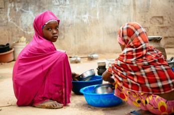 Two young girls washing dishware.