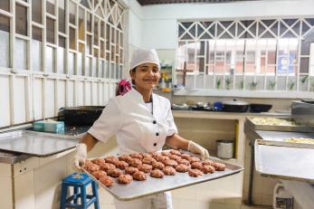 Woman in colombia holding a pan of baked goods