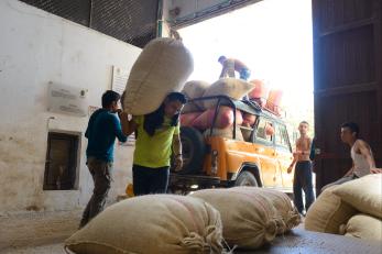 Men in a warehouse loading large canvas bags