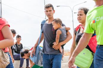 Dad holding a baby walking across the venezuela and colombia border