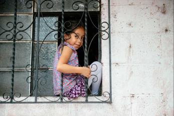 Young girl sitting on a window ledge.