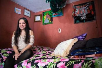 Young guatemalan woman sitting on her bed.