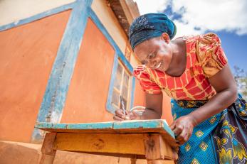 Kenyan woman smiling while writing at a table