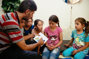 Ziad drawing and showing illustrations to a group of children