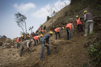 Nepalese road construction crew working on hillside.