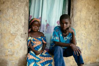 Brother and sister sitting in doorway of home.