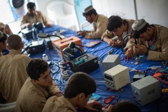 Young men sitting around a table working to repair cell phones