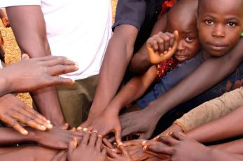 Hands reaching into the center of a circle with two children in the corner in car