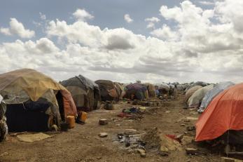 Tents are set up close together along a dry dirt path