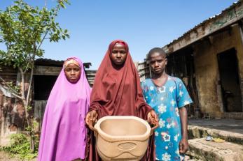 Three siblings standing together outside their home.