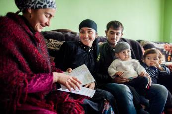 A community health educator visiting with a couple and their young children